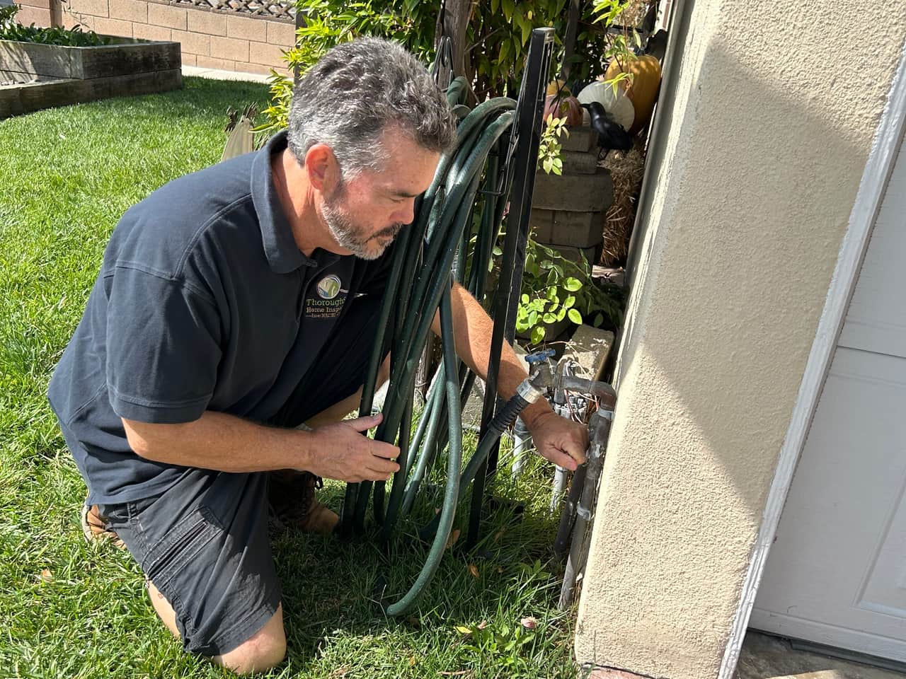 Mark Kinder checking a home's exterior water connections during a home inspection