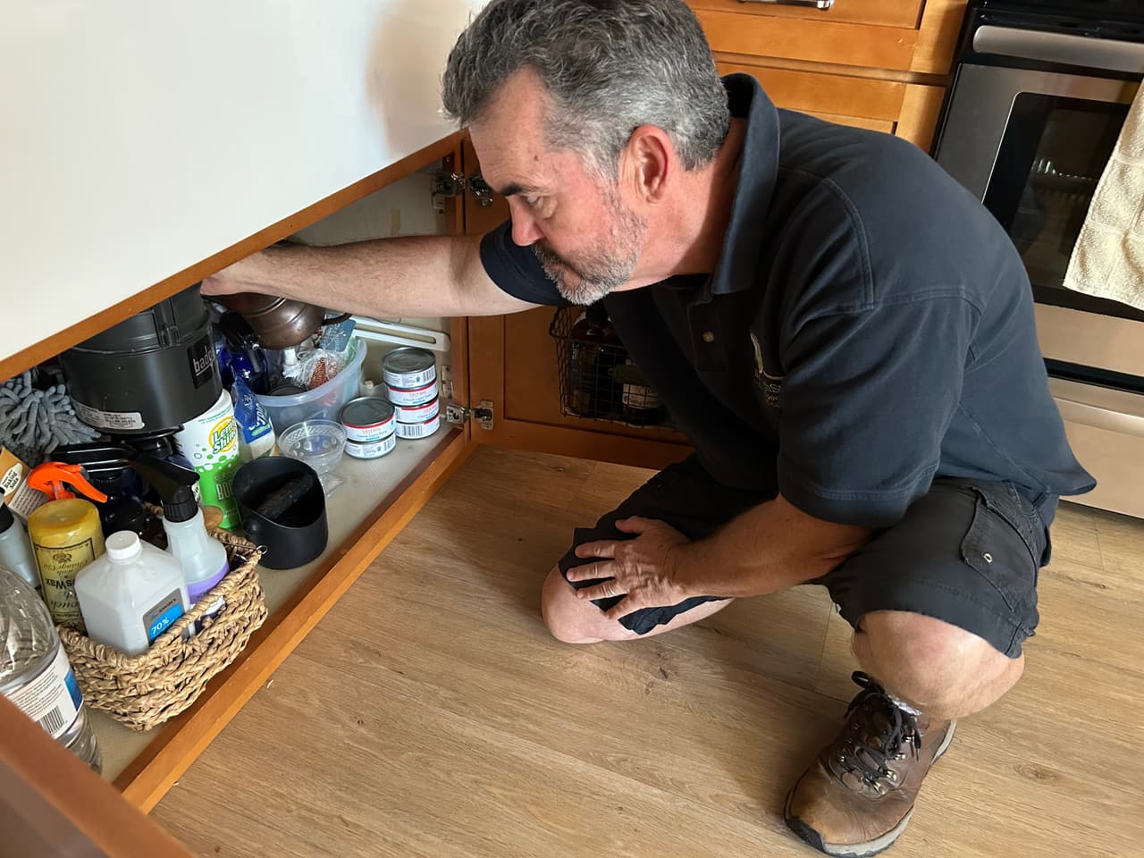 Mark Kinder inspecting under a kitchen sink during a home inspection